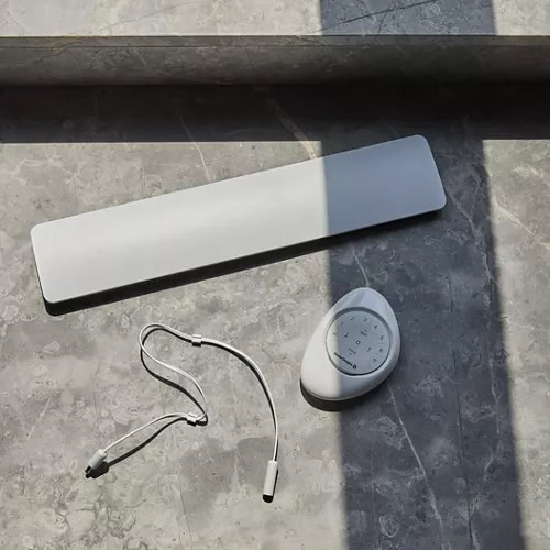 Wireless outdoor shower heater with digital control panel, mounted on gray stone tile surface for optimal outdoor shower experience.