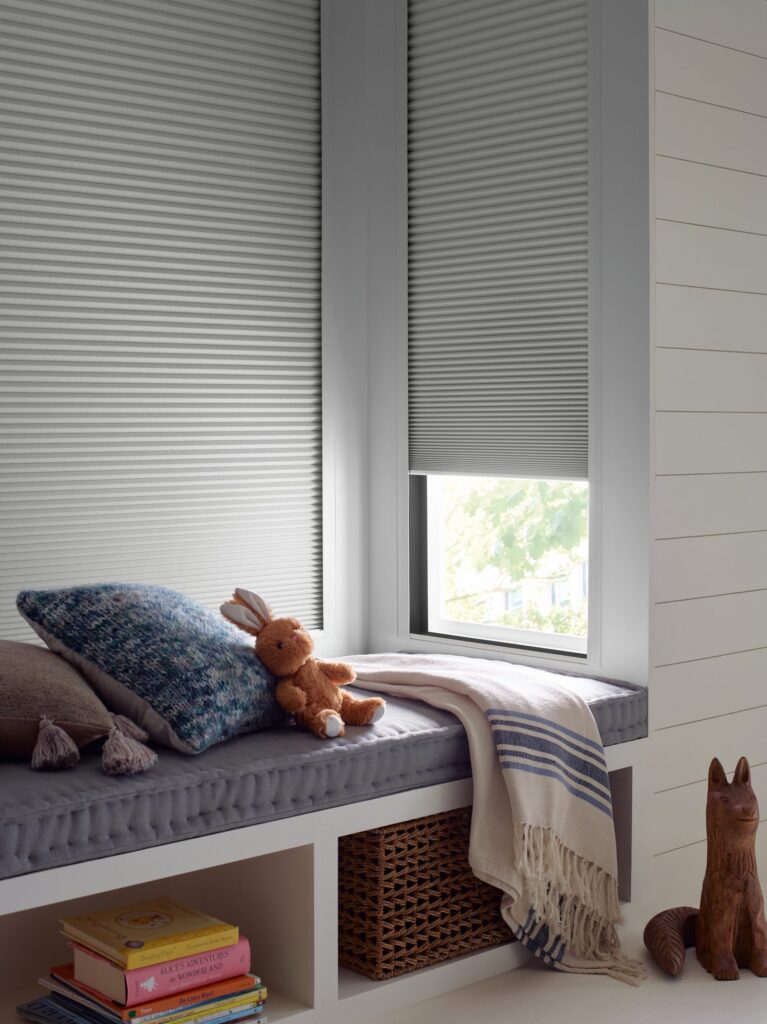 Duette® Honeycomb Shades with the LightLock® system above a kids’ room window seat